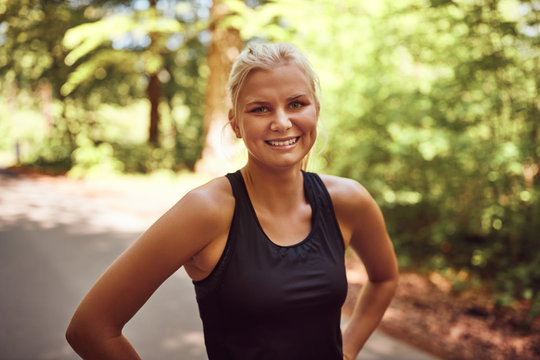 Sporty young blonde woman smiling before her forest run