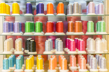 Colorful embroidery thread spool using in garment industry, row of multicolored yarn rolls, sewing...