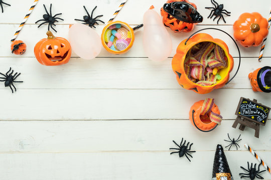 Table top view aerial image of decoration Happy Halloween day background concept.Flat lay accessories essential object to party the pumpkin & sweet candy on white wooden.Space for creative design.