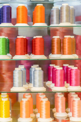 Background with a lot of colorful coils with threads. Bobbins are stacked in three rows, one on the other. The winding is erratic. Multicolored threads BANNER, vertical photo
