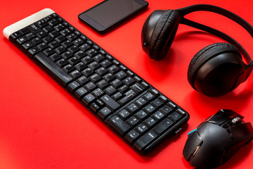 Game keyboard, headphones, mouse accessories for a gamer on a red background.  flat lay top view with a copy space