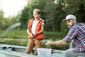 Amazed boy looking at bending rod while big fish in appearing in water - Powered by Adobe