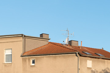 tv antenna and satellite dish on an old house roof