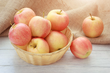 Tasty red and yellow apple fruits on wooden white background in wicker basket