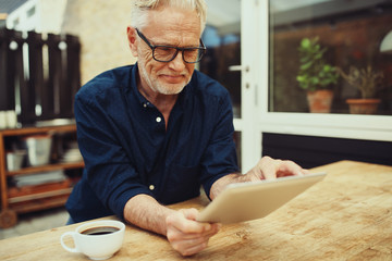 Content senior man using a tablet on his patio