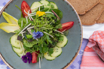 Frischer Markt gemischter Salat mit Blumen und Kräutern im Biergarten serviert