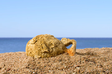 Fototapeta na wymiar Ancient amphora lying on the sand against the blue sky, found in Greece