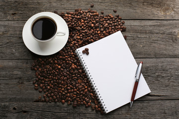 Obraz na płótnie Canvas Cup of coffee with coffee beans and notebook
