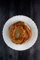 a stack of potato pancakes on a white plate on a wooden background. Home kitchen.