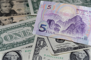 Banknote of five Chinese yuan against background of american dollars