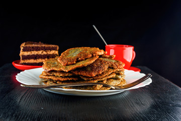 a stack of potato pancakes on a white plate on a wooden background. Home kitchen.