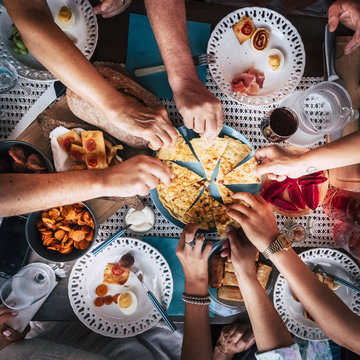 Aerial view from above for table and hands and a lot of food and drinks. celebration and party event concept image. all hands taking from the same plate to share and enjoy the friendship. 
