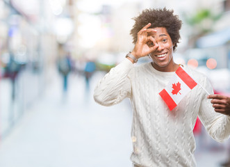 Afro american man flag of Canada over isolated background with happy face smiling doing ok sign with hand on eye looking through fingers