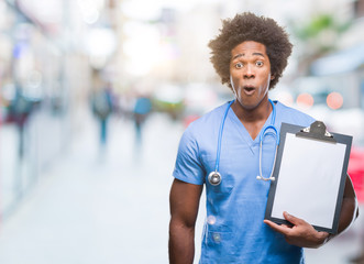 Afro american surgeon doctor holding clipboard man over isolated background scared in shock with a surprise face, afraid and excited with fear expression