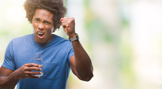 Afro american man drinking glass of water over isolated background annoyed and frustrated shouting with anger, crazy and yelling with raised hand, anger concept