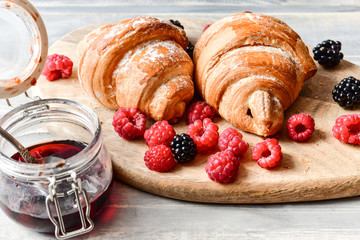coffee with milk and croissants, jam and fresh raspberries and blackberries on a wooden table. on the Cup inscription in French (mocha coffee, coffee with milk