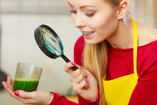 Woman looking at vegetable juice through magnifying glass
