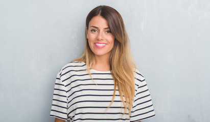 Young adult woman over grunge grey wall wearing navy t-shirt with a happy and cool smile on face. Lucky person.