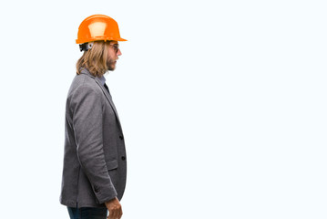 Young handsome architec man with long hair wearing safety helmet over isolated background looking to side, relax profile pose with natural face with confident smile.