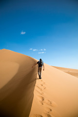 Fototapeta na wymiar One person climbing big dune in the desert