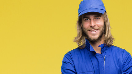 Young handsome mechanic man with long hair over isolated background happy face smiling with crossed arms looking at the camera. Positive person.