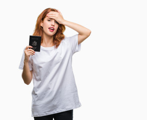 Young beautiful woman holding passport of united states of america over isolated background stressed with hand on head, shocked with shame and surprise face, angry and frustrated. Fear and upset