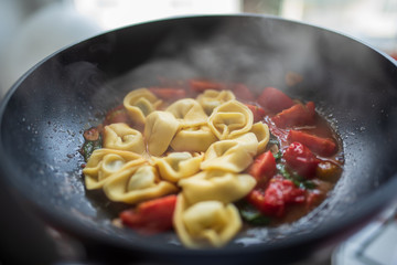 Italienisches Essen gefüllte Tortellini mit Tomaten Ragout Soße in einer Pfanne Topf am kochen mit Dampf 