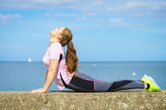 Woman doing yoga next to sea