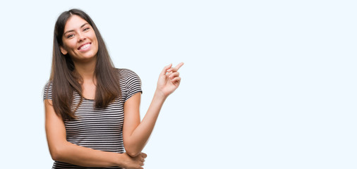 Obraz premium Young beautiful hispanic woman with a big smile on face, pointing with hand and finger to the side looking at the camera.