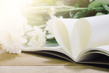 Heart shape paper book on wood table with white cosmos flower