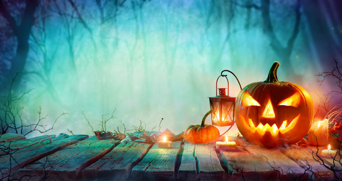 Halloween - Jack O' Lanterns And Candles On Table In Misty Night
