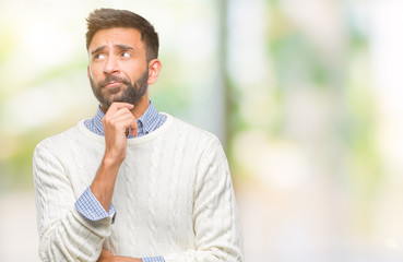 Adult hispanic man wearing winter sweater over isolated background with hand on chin thinking about question, pensive expression. Smiling with thoughtful face. Doubt concept.