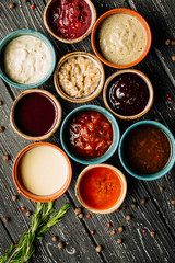 Set of different sauces on black wooden background. Top view