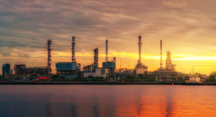 panorama view of petrochemical refinery oil energy plant factory industrial the fuel power storage design on morning skyline with sunshine at golden hour in sky with reflection on water riverside.