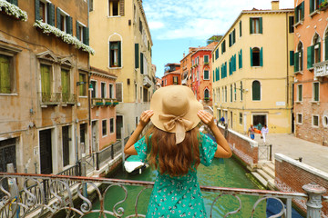 Fototapeta premium Sweet romantic girl charmed by Venice landscape. Rear view of female tourist on a bridge in Venice, Italy.