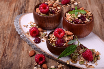Granola decorated with raspberries in wooden cups on the table