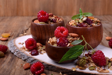 Granola decorated with raspberries in wooden cups on the table