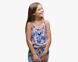 Young beautiful girl wearing colorful dress over isolated background looking away to side with smile on face, natural expression. Laughing confident.