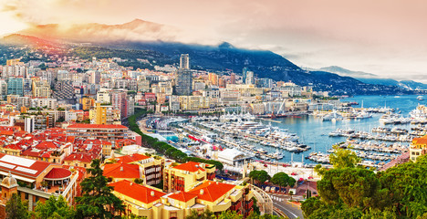 Principality of Monaco. Picturesque panoramic view on Monaco on sunset hour. View on apartment building, casino, port with luxury yachts. Monaco is popular travel destination for gambling.  - obrazy, fototapety, plakaty