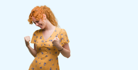 Young redhead woman very happy and excited doing winner gesture with arms raised, smiling and screaming for success. Celebration concept.