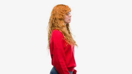 Young redhead woman wearing red sweater looking to side, relax profile pose with natural face with confident smile.