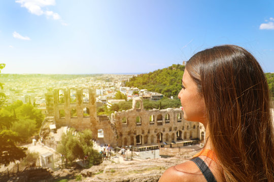 Young woman on the Acropolis of Athens, Greece. Tourist female looking to ancient theater and Athens landscape in a summer day on the Acropolis.