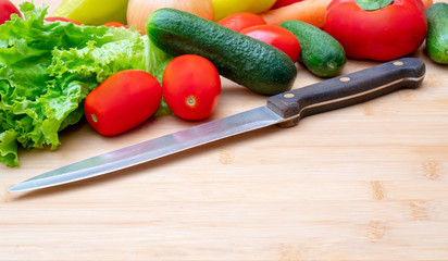 Vegetables on wooden cutting board. Vegetables: lettuce, onions, tomatoes, cucumbers, onions, carrots, red sweet peppers.