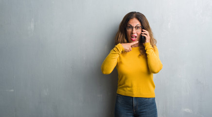 Middle age hispanic woman talking on the phone very happy pointing with hand and finger