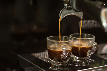 closed-up espresso machine brewing coffee in two shot glasses throgh portafilter