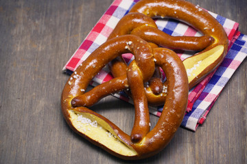 Two pretzels with checker cloth on wood table background.