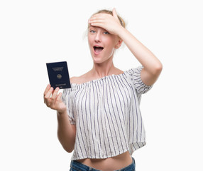 Naklejka premium Blonde teenager woman holding passport of Germany stressed with hand on head, shocked with shame and surprise face, angry and frustrated. Fear and upset for mistake.