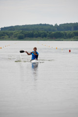 Young sportsman paddling on the river during competition