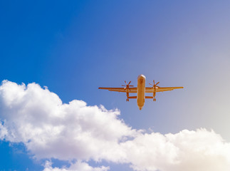 airplane flying against blue sky, white clouds behind