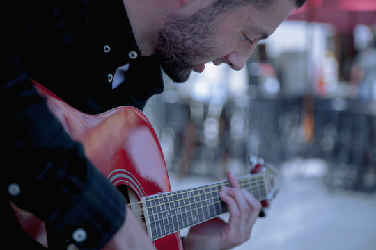 A Busker singing and playing guitar on the streets of old European city. Caucasian man playing the guitar outdoors.